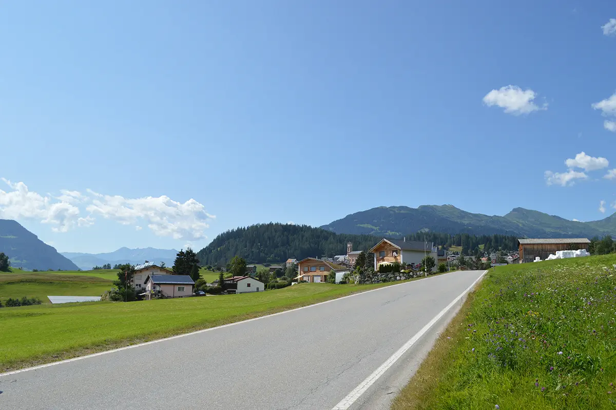 Straßenpanorama mit den Häusern des Quartier La Pala in der alpinen Landschaft